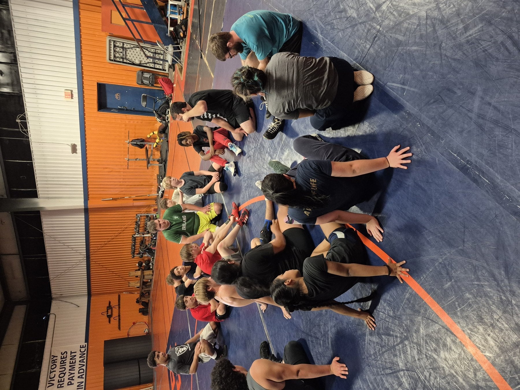 Coaches teaching technique to wrestlers on the practice mat